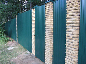 Комбинированный забор с кирпичными столбами на фото от компании Комфорт у дома